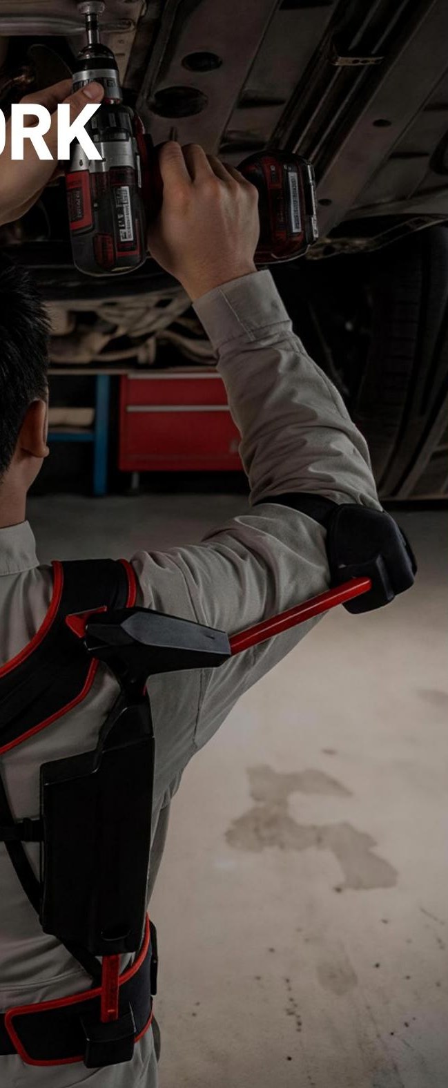 Technician working under a vehicle while wearing the AP2 arm support exoskeleton